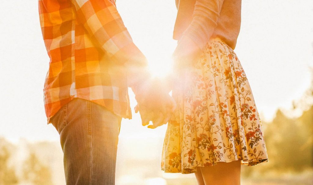 Young couple in love walking in the autumn park holding hands