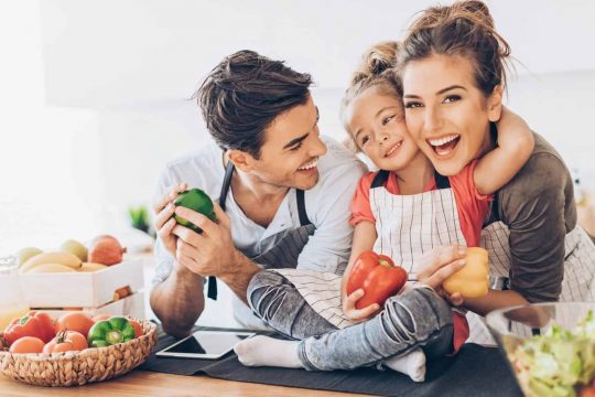 Young couple with small girl in the kitchen.